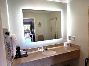 baño con lavabo y espejo grande en Days Inn by Wyndham Pensacola - Historic Downtown, en Pensacola