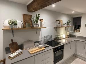 a kitchen with white cabinets and a stove top oven at BEECH COTTAGE in Hatherop