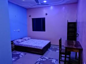 a bedroom with a bed and a table and a desk at CHEZ ALFA in Djougou