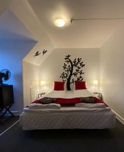 a bedroom with a bed with a tree on the wall at Otel Vaabensted in Sakskøbing