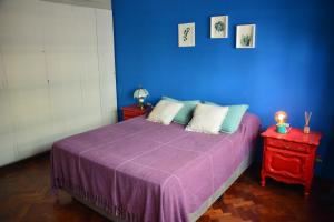 Dormitorio azul con cama con manta morada en Casabunda habitación privada en el centro en Salta