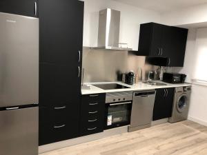 uma cozinha com armários pretos, um lavatório e um fogão em PARQUE DE LA MARINA ESPAÑOLA em Zamora