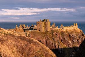 a castle on a cliff next to the ocean at Beach View Apartment in Stonehaven