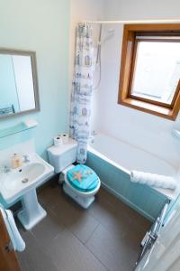 a bathroom with a toilet and a tub and a sink at Beach View Apartment in Stonehaven