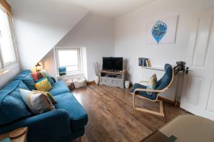 a living room with a blue couch and a chair at Beach View Apartment in Stonehaven