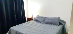 1 cama con edredón azul y almohada en DEPTO CENTRO SALTA. DEAN FUNES 45 en Salta
