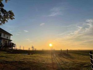 un coucher de soleil sur un champ avec une clôture dans l'établissement Breathtaking Rustic Farmhouse Getaway, à Seward