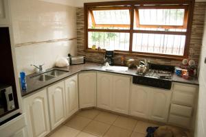 cocina con armarios blancos, fregadero y ventana en Santa Cruz 5761 en Mar del Plata