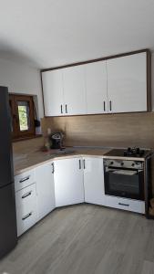 a kitchen with white cabinets and a stove at Vikendica Pašter in Šipovo