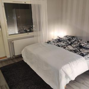 een wit bed in een slaapkamer met een raam bij Kodikas kaksio keskustassa in Pori