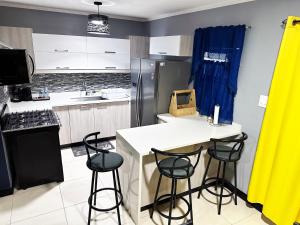 a kitchen with a white counter and stools in it at Luxury Crib 5 mins from the NMIA airport in Kingston
