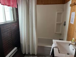 a bathroom with a white shower curtain and a sink at La Cabane chez Jimmy in Petit-Saguenay
