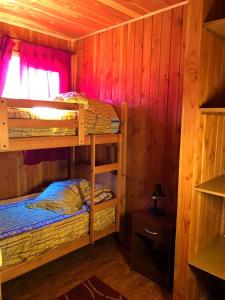 2 stapelbedden in een houten kamer met een raam bij CABAÑAS MILKAHUE PUCON in Pucón