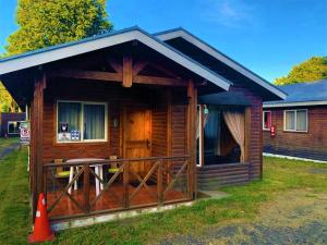 een blokhut met een veranda en een terras bij CABAÑAS MILKAHUE PUCON in Pucón