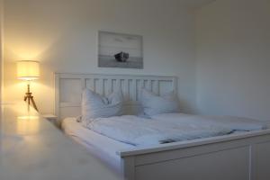 een witte slaapkamer met een wit bed en een lamp bij Ferien in Finning - im traumhaften Fünfseenland in Finning