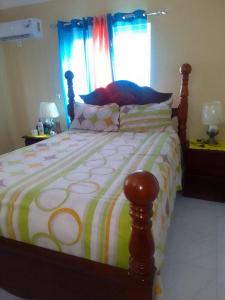 um quarto com uma cama grande e uma colcha colorida em Simpson's residence em Lucea