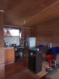 a kitchen with a stove and a counter with two stools at Cabañas Tepual in Puerto Montt