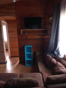 sala de estar con sofá y TV de pantalla plana en Cabañas Tepual en Puerto Montt