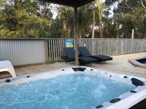 a hot tub on a deck with two chairs at Elk Estate in Inverloch
