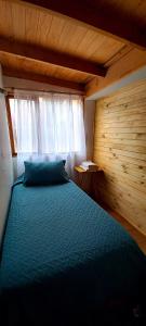 ein Schlafzimmer mit einem blauen Bett in einem Holzzimmer in der Unterkunft Cabaña en Los Romeros Con Con in Concón