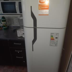 - un réfrigérateur blanc dans une cuisine à côté d'un four micro-ondes dans l'établissement Hospedaje Champaqui, à Santa Rosa de Calamuchita