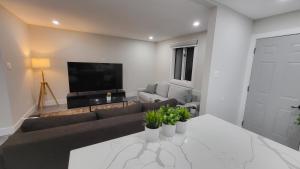 ein Wohnzimmer mit einem Sofa und einem TV in der Unterkunft JstLikeHome - Serenity Suites in Ottawa
