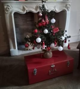 a christmas tree on a red trunk in front of a fireplace at Domaine de Pladuc in Lachaise