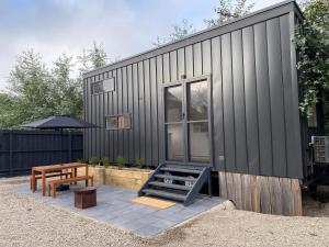 a black house with a picnic table and a bench at Tiny House Clunes at The Old Butter Factory in Clunes