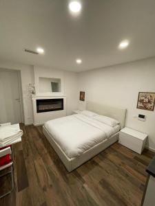 ein Schlafzimmer mit einem weißen Bett und einem Kamin in der Unterkunft Luxury 1 al Duomo di Parma in Parma