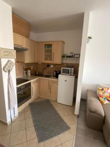 a small kitchen with wooden cabinets and a couch at Gyöngy Apartman in Sopron