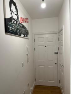 einen Flur mit einer weißen Tür und einem Autobild an der Wand in der Unterkunft Modern and Stylish 1bed flat in Barking