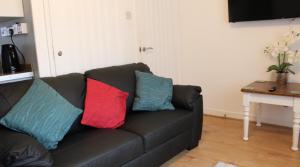 a black couch with three colorful pillows on it at 2 bedroom Chalet all to yourself, free parking, dogs welcome in Swansea