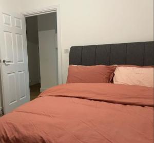 a bedroom with a bed with orange sheets and pillows at Modern and Stylish 1bed flat in Barking