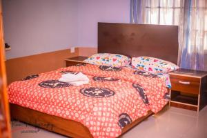 een slaapkamer met een bed met een rode deken en kussens bij Dayspring Apartments. Entire house for guests. Ekiti in Ado Ekiti