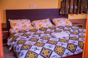 a bed with a comforter and pillows on it at Dayspring Apartments. Entire house for guests. Ekiti in Ado Ekiti