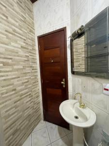 baño con lavabo y puerta de madera en Smart Suíte en Boa Vista