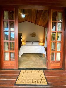 Chalés Vila Do Vale في فالي دو كاباو: غرفة نوم مع سرير في غرفة مع نوافذ