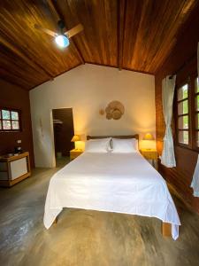 sypialnia z dużym białym łóżkiem i drewnianym sufitem w obiekcie Chalés Vila Do Vale w mieście Vale do Capao