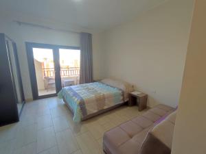 a bedroom with a bed and a couch and a balcony at Lovely studio Al-Dau Heights in Hurghada