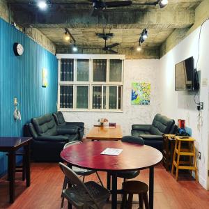 a room with a table and couches and a table and chairs at Tainan Guest House Hamuya in Tainan