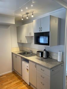 a kitchen with white cabinets and a sink at St Andrews Unit in Hamilton