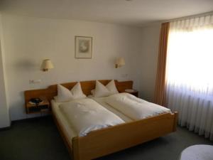 a bedroom with a bed with white sheets and a window at Hotel Restaurant Adler Bühlertal in Bühlertal