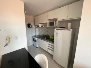 una pequeña cocina con armarios blancos y nevera. en Apart 302 no José Américo, en João Pessoa