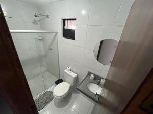 y baño blanco con aseo y ducha. en Apart 302 no José Américo, en João Pessoa