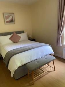 a bedroom with a bed with a bench next to a window at Glengesh Court. Ardara town centre. in Ardara