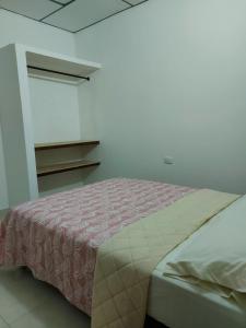 a bedroom with a bed with a pink and white bedspread at Guio Apartamentos in San Antero