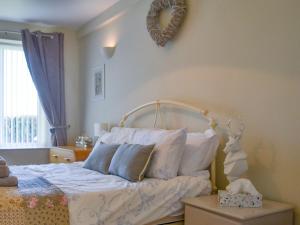 a bedroom with a bed with white sheets and pillows at Red Hen Cottage in Broomhill