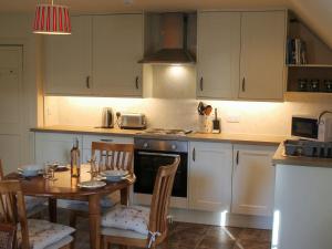 a kitchen with a table and chairs and a kitchen with white cabinets at The Courtyard Suite in Oathlaw