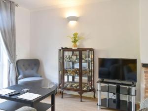 a living room with a tv and a chair and a table at Stone Gardens in Broadstairs