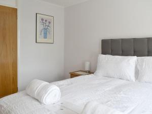 a bed with white sheets and a picture on the wall at Stone Gardens in Broadstairs